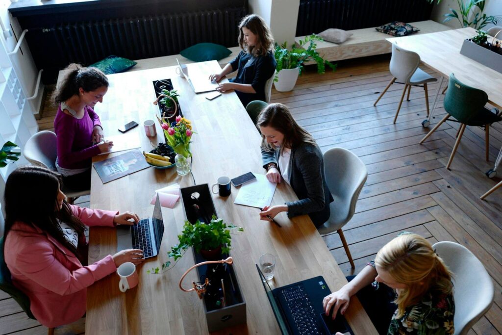 Team am Holztisch beim Meeting mit Laptops – Google Ads Agentur vs. Freelancer