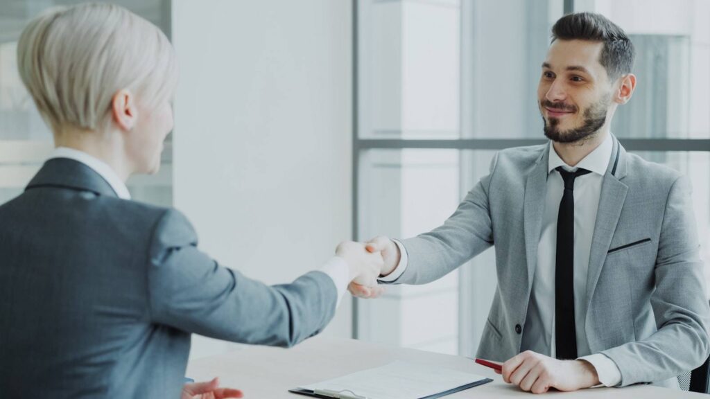 Zwei Geschäftsleute beim Handshake über einen Schreibtisch – Google Ads für B2B